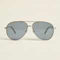 Amelie wide aviator sunglasses in brushed silver with grey lenses, against a cream studio backdrop