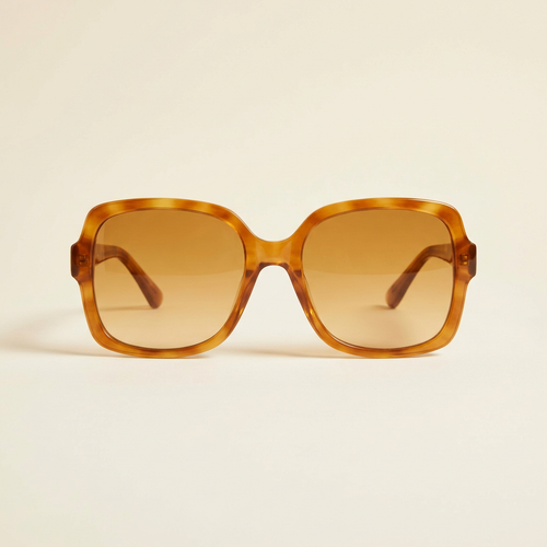 Aurore oversized retro sunglasses in honey tortoiseshell with amber lenses, against a cream studio backdrop