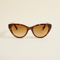 Elodie vintage cat-eye sunglasses in tortoiseshell with amber lenses, against a cream studio backdrop