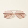 Solene slim aviator sunglasses in rose gold with blush lenses, against a cream studio backdrop